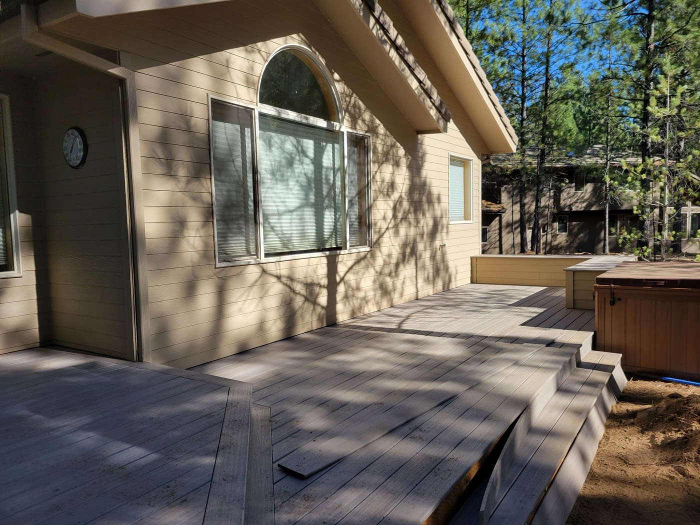 Deck running along the home toward the hot tub and privacy wall